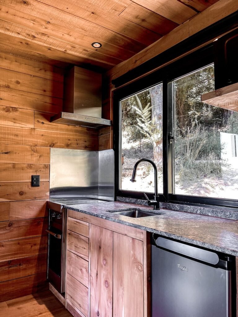 Equipped kitchen with a sink and a window onto the forest