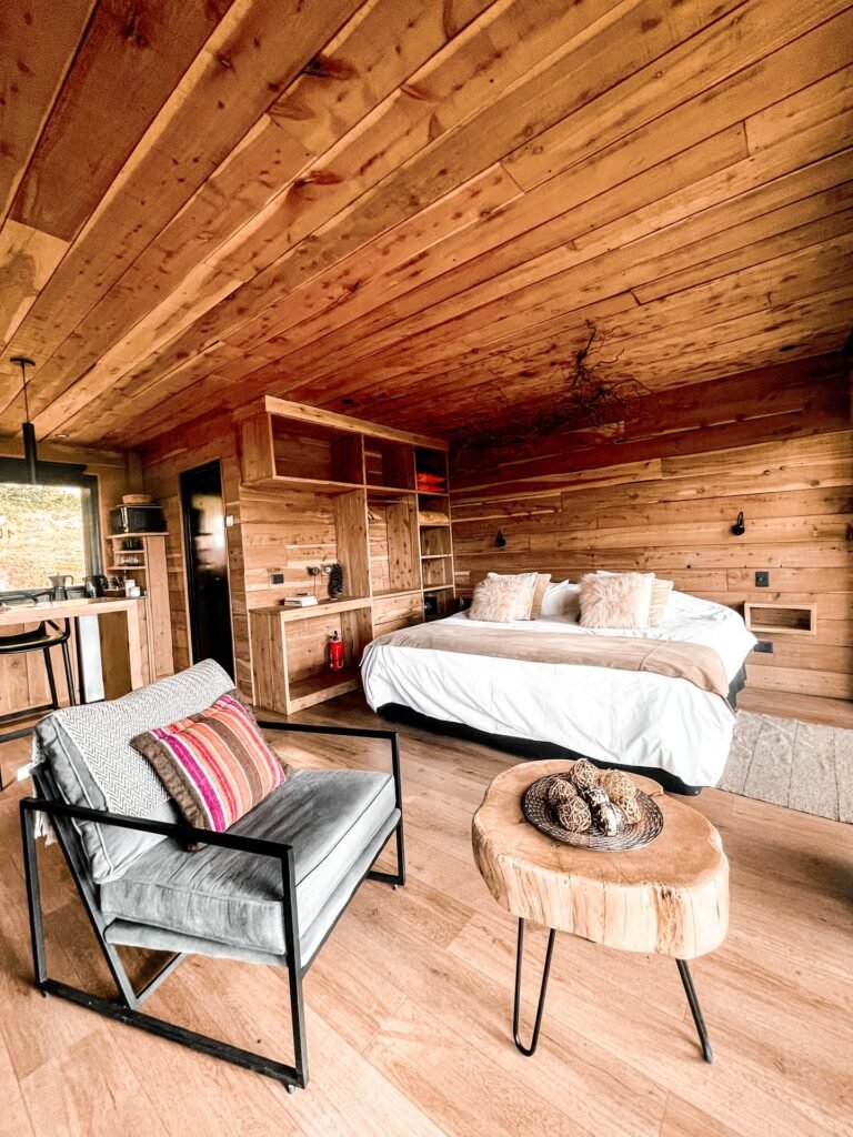 Inside the tiny house: armchair, king-size bed and kitchen in one open wooden space